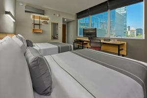 Habitación de hotel con 2 camas y TV de pantalla plana. en City Express Plus by Marriott Monterrey Nuevo Sur en Monterrey