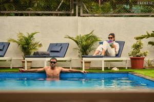 a man and a woman sitting in chairs in a swimming pool at EKOSTAY - Luxe - La Casa Grande in Lonavala