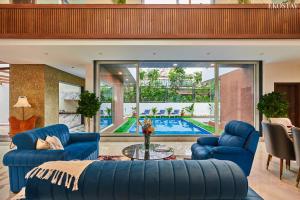 a living room with blue furniture and a swimming pool at EKOSTAY - Luxe - La Casa Grande in Lonavala