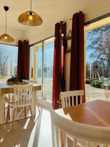 Mesves-sur-LoireにあるMotel Les Broussaillesの赤いカーテン、テーブルと椅子付きのダイニングルーム