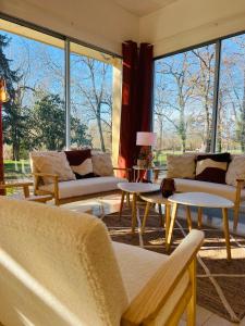 una sala de estar con sofás, mesas y ventanas grandes. en Motel Les Broussailles, en Mesves-sur-Loire