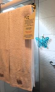 un asciugamano e un cartello su una porta di vetro con una farfalla di Suítes Cambucá a Ilhabela