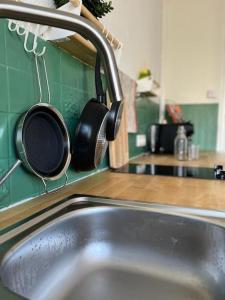 - un évier de cuisine avec des casseroles suspendues à un robinet dans l'établissement Joli appartement en duplex, parking privé Hortillonage, à Amiens