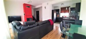 a living room with a black couch and a red wall at House between Cracow and Wieliczka in Wieliczka