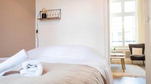 1 dormitorio con 1 cama blanca y 1 silla en L'hôtel de ville - Joli petit T2 en centre-ville, en Poitiers