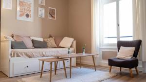 ein Wohnzimmer mit einem Sofa, einem Tisch und einem Stuhl in der Unterkunft L'hôtel de ville - Joli petit T2 en centre-ville in Poitiers