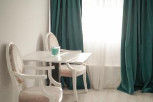un tavolo bianco con sedie e una tazza sopra di VIVERIA a Oradea