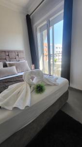 1 dormitorio con 2 camas con sábanas blancas y ventana en Appart Hotel Tanger Paname en Tánger