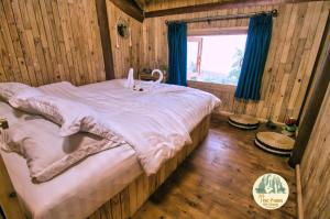duże łóżko w drewnianym pokoju z oknem w obiekcie TVpalm Ecolodge w mieście Hà Giang