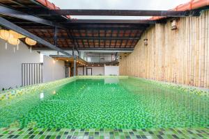 una piscina llena de azulejos de cristal verde en La An Old Town Hotel, en Hoi An
