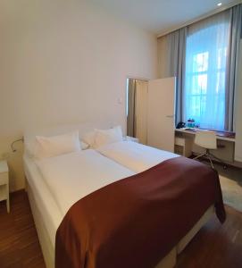 a bedroom with a large white bed and a desk at Hotel Am Domplatz - Adult Only in Linz