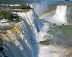 a rainbow at the bottom of a waterfall at Hostel Damaris in Puerto Iguazú