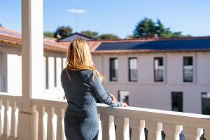 Eine Frau steht auf einem Balkon mit Blick auf ein Gebäude in der Unterkunft VIA VITTORIO VENETO 468 CHIARI in Chiari