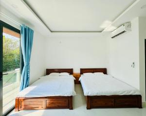 2 camas en una habitación con ventana en Lava Rock Viet Nam Lodge, en Cát Tiên