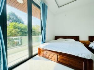 a bedroom with a bed and a large window at Lava Rock Viet Nam Lodge in Cat Tien