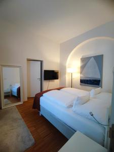 a bedroom with a large white bed and a mirror at Hotel Am Domplatz - Adult Only in Linz