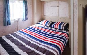 Bett mit gestreifter Decke auf einem Zimmer in der Unterkunft Lovely Home In Mielno With Kitchen in Mielno
