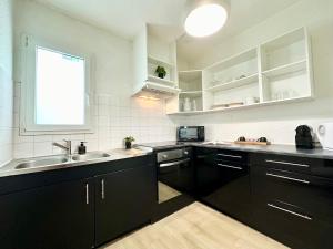 a kitchen with black cabinets and a sink and a window at LE COSY - Plain-Pied in Mont-de-Marsan