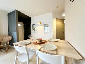 a dining room with a wooden table and white chairs at LO CAMIN - Cosy - Plain-Pied - Hyper Centre in Mont-de-Marsan