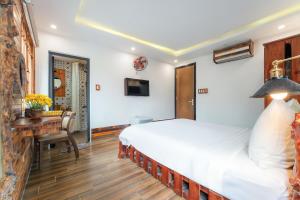 a bedroom with a large bed and a desk at La An Old Town Hotel in Hoi An