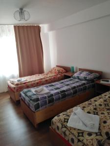 ein Hotelzimmer mit 3 Betten und einem Fenster in der Unterkunft Apartament S&F in Dej