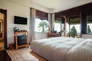 a bedroom with a bed and a flat screen tv at Girihill Farmhouse in Munduk