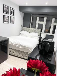 a bedroom with a bed and a table with red flowers at Letzi Private En-Suite In Harrow in Pinner
