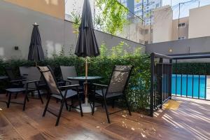 聖保羅的住宿－Exclusivo na Liberdade com Piscina e Wi-fi 300mb，一个带桌椅和遮阳伞的庭院。