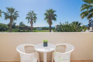 a white table and chairs with palm trees in the background at Cavo D'oro Resort in Kalamaki +13 photos