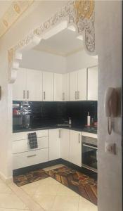 uma cozinha com armários brancos e electrodomésticos pretos em Luxury appartment Oumi em Martil