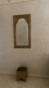 Luxury appartment Oumi في مرتيل: مرآة على جدار أبيض مع صندوق خشبي