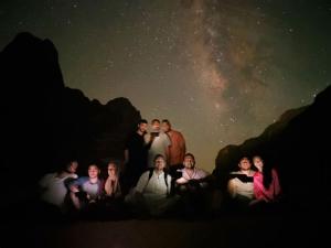 a group of people posing for a picture under the night sky at SARA lUXURY CAMP in Disah