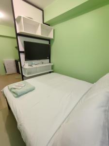 a bedroom with a white bed and a tv at Tower 3 208 Sunset View in Iloilo City