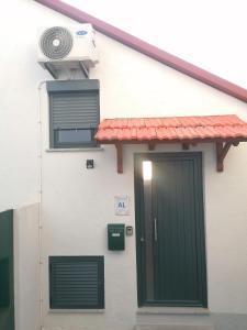 a white house with a green door and a fan at CASA do AÇÔR in Aldeia das Dez