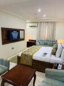a bedroom with a bed and a tv and a couch at Qualibest Grand Hotels in Abuja