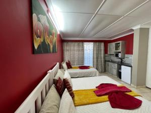 a bedroom with two beds and a red wall at Che La Moir Guesthouse in Bloemfontein