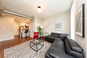 uma sala de estar com um sofá de couro preto e uma cadeira vermelha em The Secret West Loop Oasis with in-unit washer and dryer for up to 6 guests em Chicago
