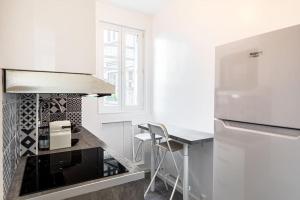 eine weiße Küche mit einer Theke und einem Tisch in der Unterkunft GuestReady - A precious gem near Paris in Asnières-sur-Seine