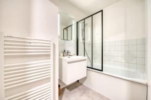 ein weißes Badezimmer mit Waschbecken und Badewanne in der Unterkunft La Perle de Houlgate Élégance & Vue 4 pers in Houlgate + 12 Fotos