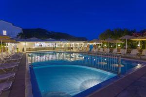 a swimming pool with chairs and umbrellas at night at Cavo Doro in Kalamaki