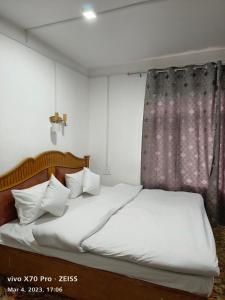 1 dormitorio con 1 cama con sábanas blancas y ventana en Royal galaxy, en Pahalgām