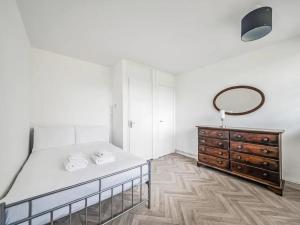 ein Schlafzimmer mit einem Bett, einem Spiegel und einer Kommode in der Unterkunft Pass the Keys Spacious Apartment in Honor Oak in London