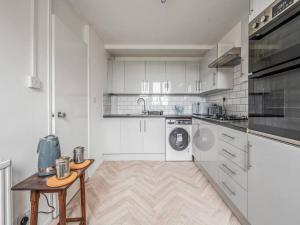 cocina con armarios blancos y mesa de madera en Pass the Keys Spacious Apartment in Honor Oak en Londres