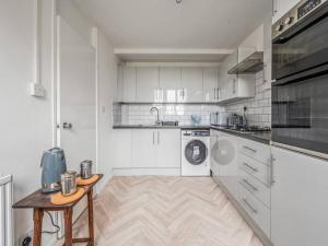 a kitchen with white cabinets and a wooden table at Pass the Keys Spacious Apartment in Honor Oak in London