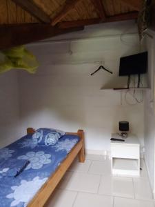 a small bedroom with a bed and a tv at STUDIO / HAUT DE VILLA / / VUE SUR MER / SALONORAT in Bouillante