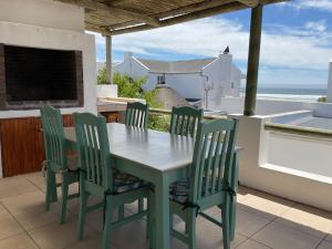 a table and chairs on a balcony with the ocean at Nova Vida in Paternoster