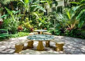 a table and benches in a courtyard with trees at Romantic Studio in the Heart of Palm Beach in Palm Beach