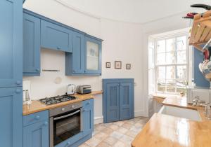eine Küche mit blauen Schränken und einer Spüle in der Unterkunft Melville Street Apartment in Edinburgh + 17 Fotos
