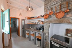 a kitchen with a stone wall with pots and pans at Tinos Traditional Patio House in Arnados