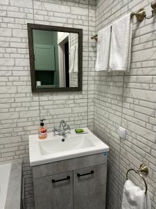 a white bathroom with a sink and a mirror at DOWNTOWN APPARTMENTS in Karagandy